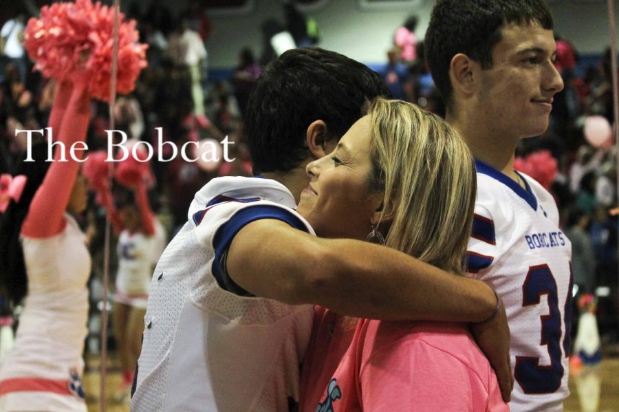 During the Pink Out pep rally which honors breast cancer survivors, sophomore, Eric Cano hugs Mrs. Tamez.