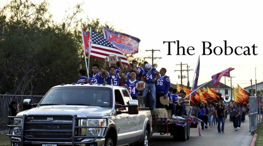 The varsity football players having fun on their float in the  homecoming parade followed by the colorguard.